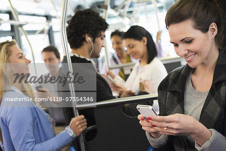 New York City park. People, men and women on a city bus. Public transport. Keeping in touch. A young woman checking or using her cell phone. New York City park. People, men and women on a city bus. Public transport. Keeping in touch. A young woman checking or using her cell phone.