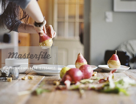 A woman in a domestic kitchen cooking. Dipping fresh organic pears into a sauce for dessert. Fresh ingredients. Brown sugar cubes