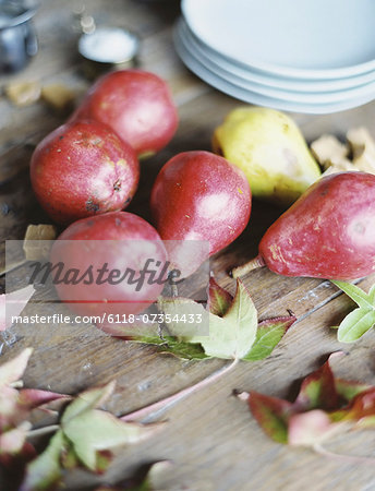 A domestic kitchen tabletop. A small group of fresh organic pears and a stack of white plates. A domestic kitchen tabletop. A small group of fresh organic pears and a stack of white plates.