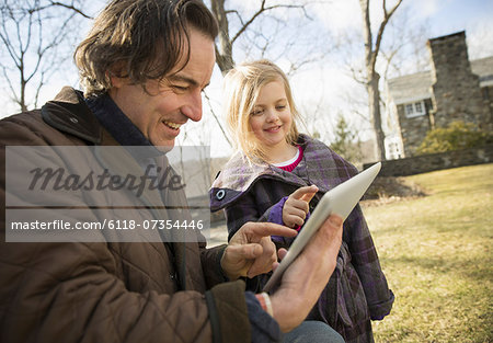 An Organic Farm in Winter in Cold Spring, New York State.  A man holding a digital tablet in his hands, showing his child the screen.