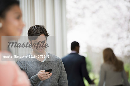 Young people outdoors on the city streets in springtime. Men and women.Two people, one checking his phone. Back view of two people in the park.