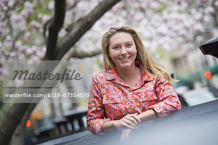 City life in spring. A young woman with long blonde hair, outdoors in a city park.