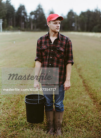 A cranberry farm in Massachusetts. Crops in the fields. A young man working on the land, harvesting the crop.