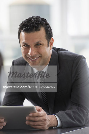 Young professionals at work. A man in a business suit, using a digital tablet.