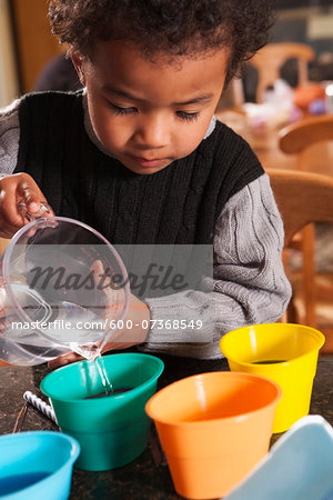 Boy Pouring Water into Dye Cups for Coloring Easter Eggs Boy Pouring Water into Dye Cups for Coloring Easter Eggs