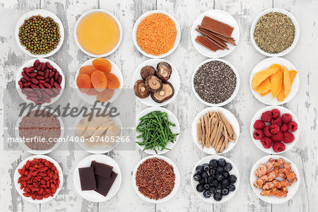 Healthy super food selection in porcelain bowls over distressed wooden background.