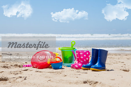Colorful plastic children's toys on the beach with sea and clouds in background