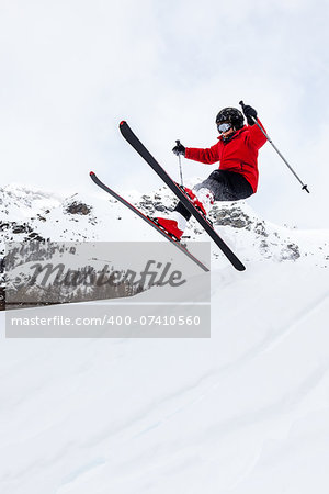 Male kid performs a high jump with the ski. Winter season, red jacket. Valle d'Aosta, Italy, Europe.