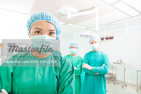 Smiling surgeon posing with a team in a surgical room