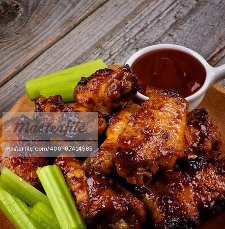 Arrangement of Celery Sticks, Ketchup and Barbecue  Chicken Legs and Wings Barbecue closeup on Wooden Plate