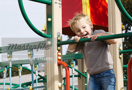 Happy little boy having fun on playground equipment and then something attracts his attention.