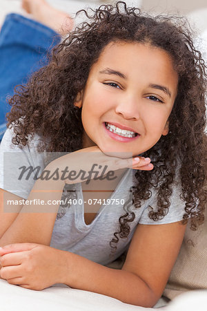 Beautiful young mixed race interracial African American girl child laying down smiling and showing off her perfect white teeth