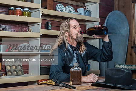 Drunk Western Man Looks Towards His Drink as he Sits at Table