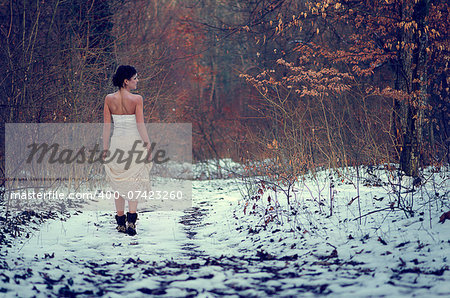 Lonely girl in white beautiful lace dress walking in a forest