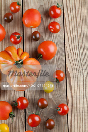 Border made from yellow, red and black tomatoes on wooden background