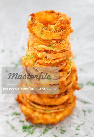 Homemade crunchy fried onion rings on a parchment. Focus on top rings