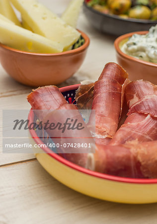 Tapas, cured ham and manchego on a white table