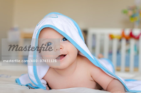 Cute little smiling baby in a hooded towel after bath