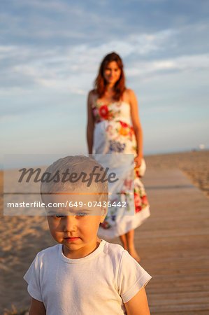 Toddler standing on boardwalk, mother in background