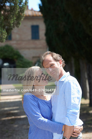 Mature couple standing in garden hugging
