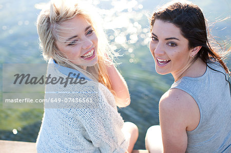Two female friends sitting on pier