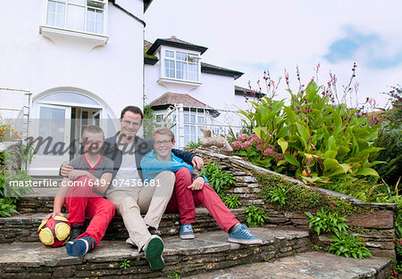 Father and sons sitting on steps in garden