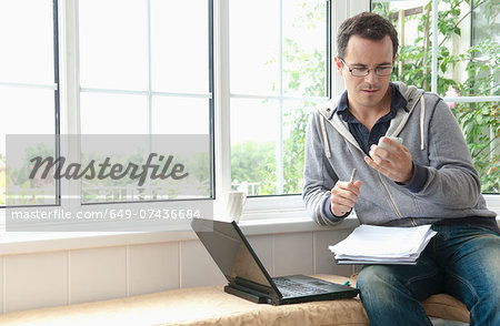 Mid adult man using mobile phone sitting in window seat