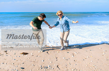 Mid adult couple fooling around on beach, Thurlestone, Devon, UK
