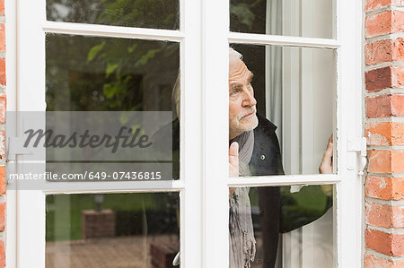 Senior man looking through window