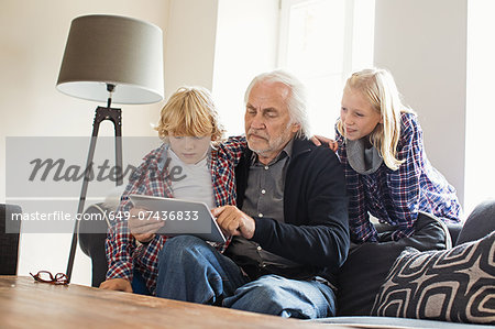 Grandfather using digital tablet with grandchildren
