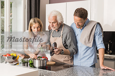 Senior man with mid adult couple preparing food