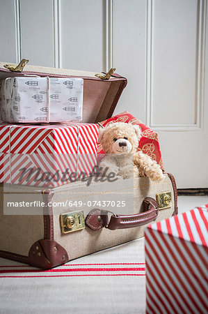 Suitcase filled with wrapped gifts and teddy bear Suitcase filled with wrapped gifts and teddy bear