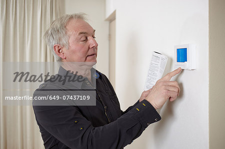 Senior man at home adjusting heating control panel