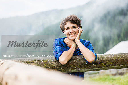 Portrait of young woman leaning against fence, Tyrol Austria