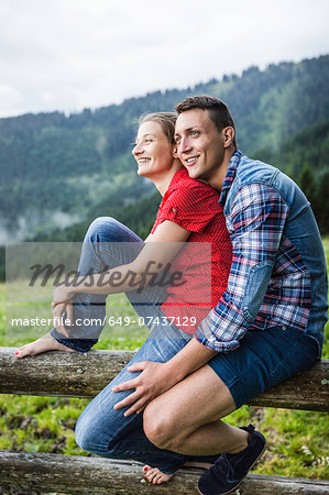 Portrait of couple sitting on fence, Tyrol Austria