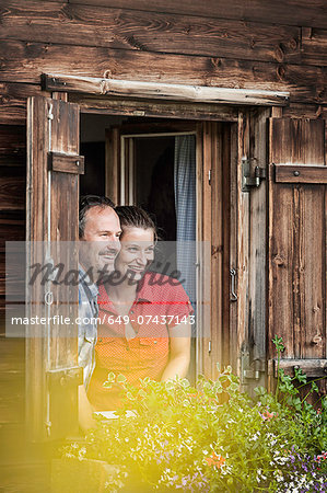 Couple looking out from chalet window, Achenkirch,  Tyrol, Austria