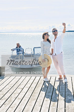 Couple photographing themselves on pier, Gavle, Sweden