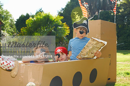 Two brothers and sister playing with homemade pirate ship in garden