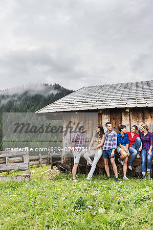 Group of friends chatting behind wooden shack, Tirol, Austria