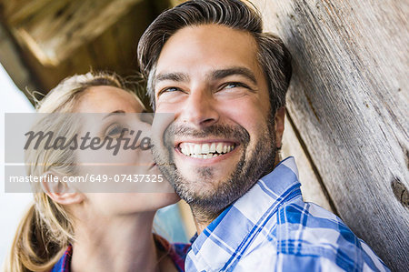 Woman kissing man's cheek outside wooden shack Woman kissing man's cheek outside wooden shack
