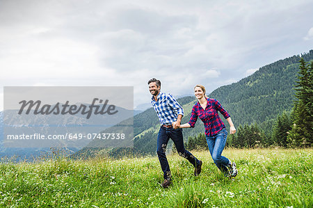 Couple holdings hands and running, Tirol, Austria