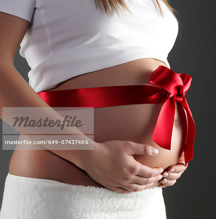 Pregnant woman's belly with red gift bow