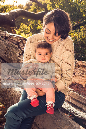 Mother and baby sitting on log