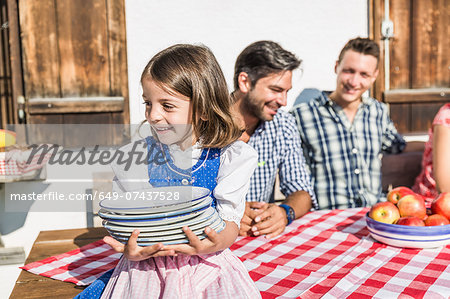 Girl carrying breakfast plates outside chalet, Tyrol, Austria