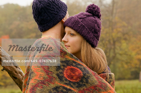 Close up of young couple wrapped in blanket in misty park