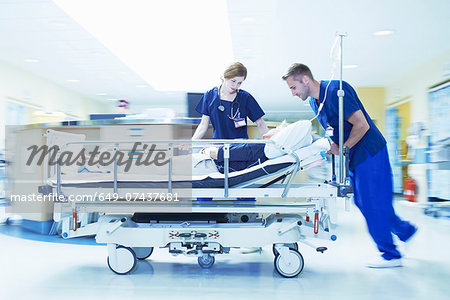 Two medics pushing gurney in hospital emergency room Two medics pushing gurney in hospital emergency room