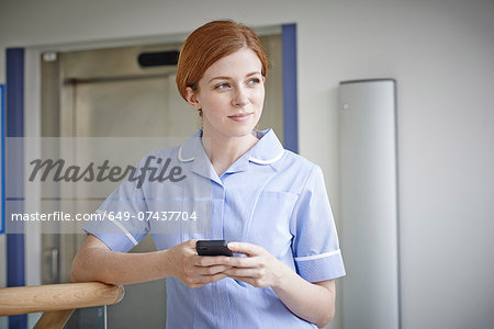 Female nurse with mobile phone outside hospital lift