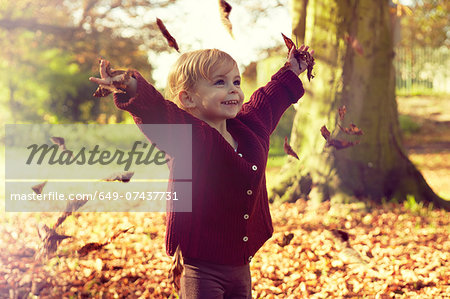 Toddler throwing autumn leaves