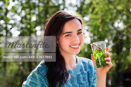 Portrait of young woman in garden with soft drink