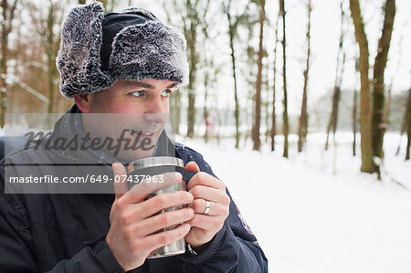 Mature man having hot drink outside in winter